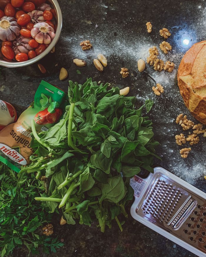Fresh vegetables, herbs, and bread on counter creating a vibrant culinary scene.